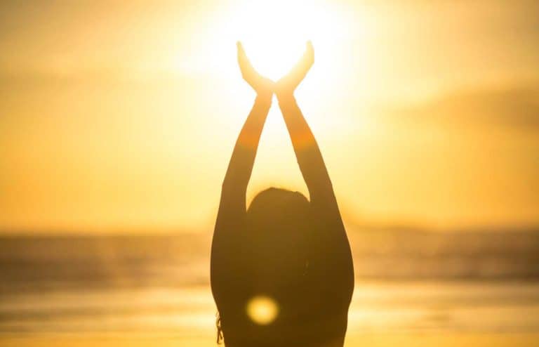 Persona practicando meditación en la playa al atardecer.