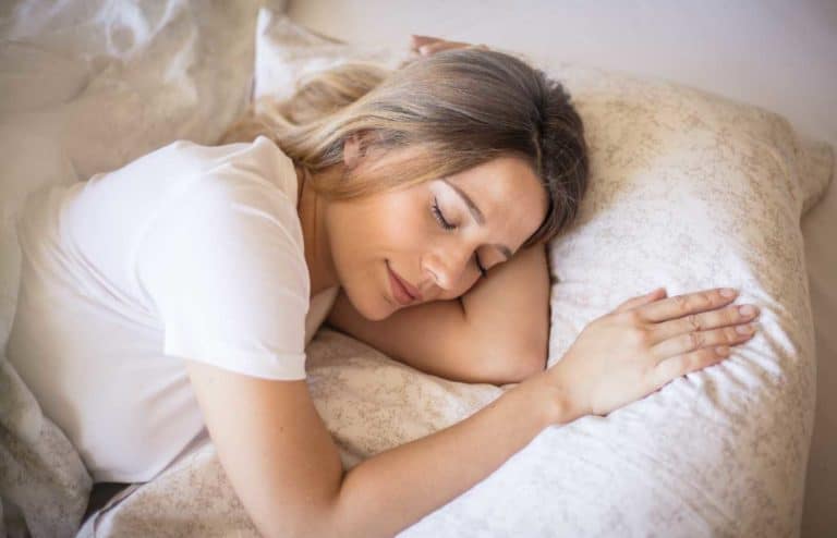 Mujer durmiendo plácidamente en cama con ambiente relajante.