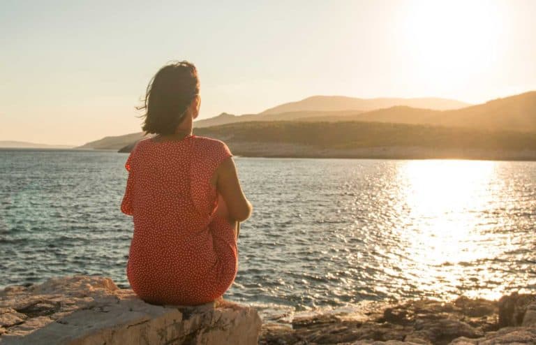 Mujer meditando frente al mar durante el atardecer en Aloha Day Spa.