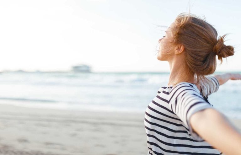 Mujer disfrutando de un momento de autocuidado en la playa.