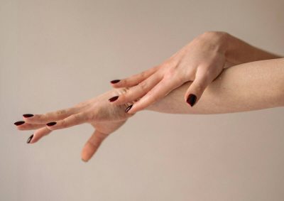 Manos con uñas esmaltadas en color burdeos, en primer plano.